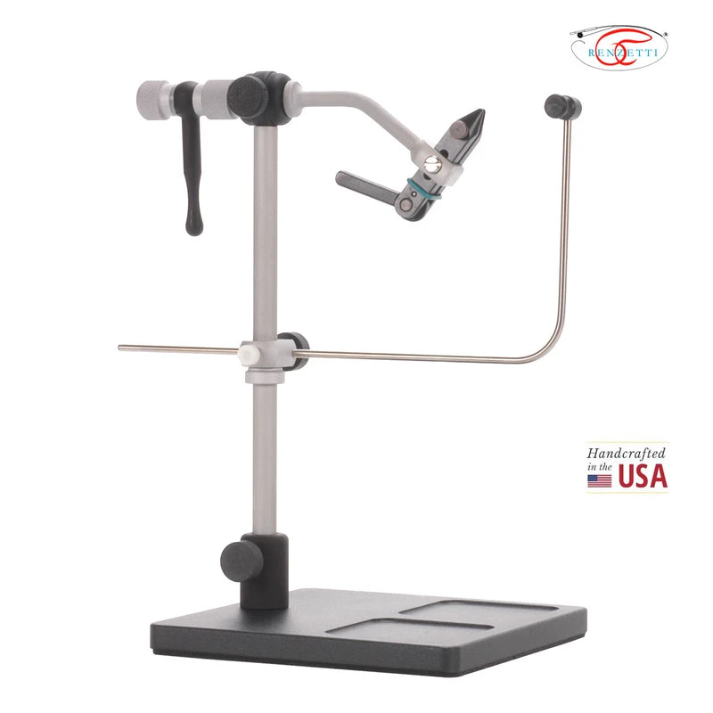 A metal and black fly-tying stand with a base, adjustable vertical clamp, horizontal wire support, and a curved hook arm holding a clamp tool, shown on a white background with a small USA-made badge and logo in the top right.